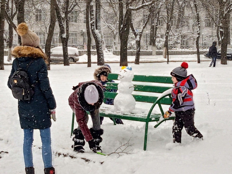 Діти ліплять сніговика в парку ОДА
